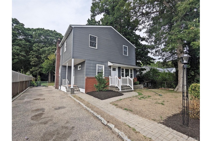 View of front of property with asphalt driveway, a chimney, and brick siding