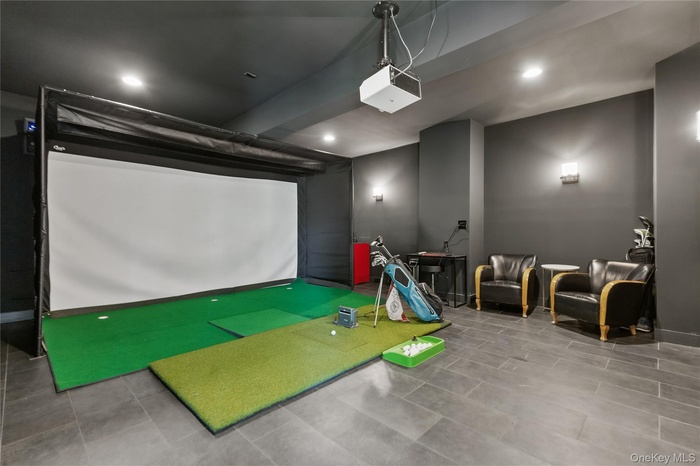 Temperature controlled golf simulator room in auxiliary garage featuring tile patterned floors