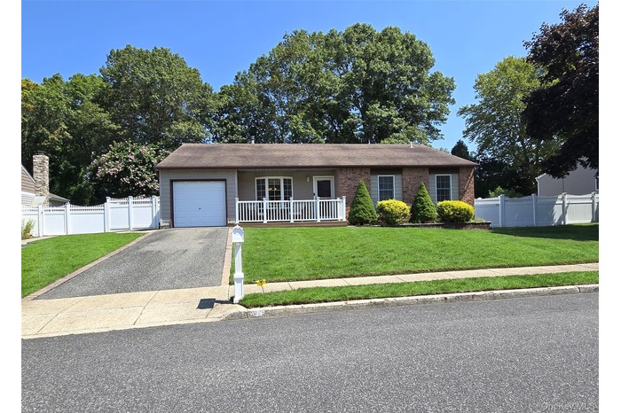 Ranch-style home featuring a garage, driveway, a porch, and brick siding