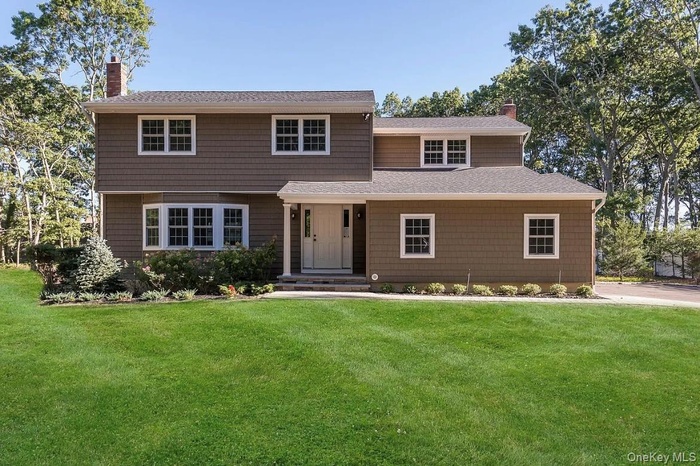 View of front of home with a chimney, a shingled roof, and a front yard