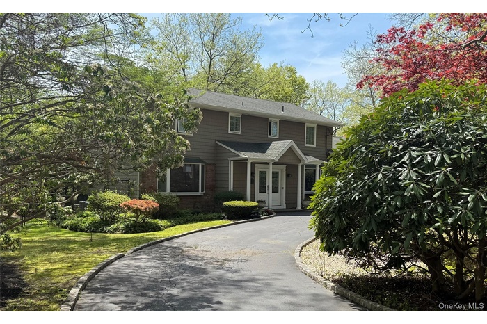 View of front of house with asphalt driveway, brick siding, and a front yard