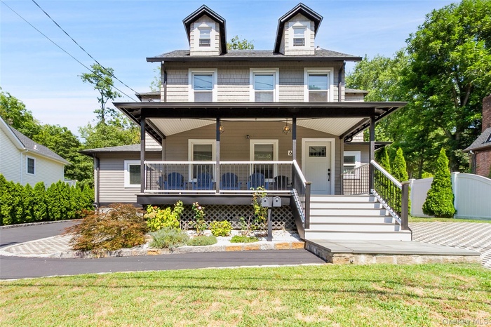 View of front of house featuring covered porch, a front lawn, and stairs