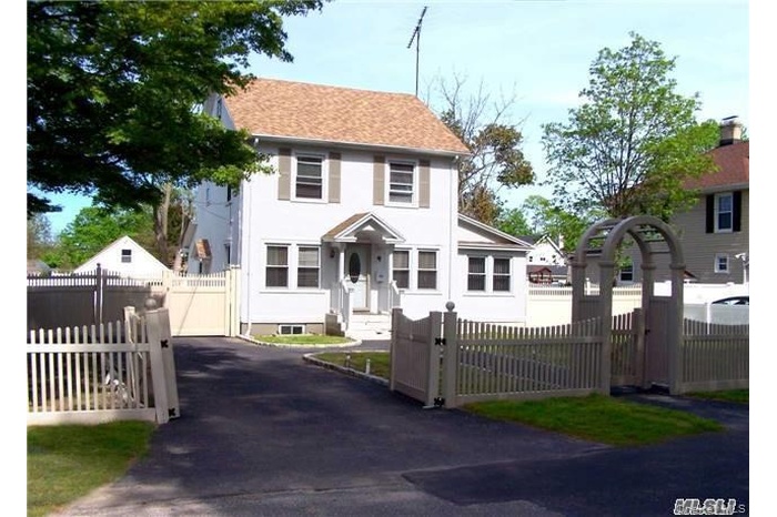 View of front of house with a gate, a fenced front yard, a shingled roof, and driveway