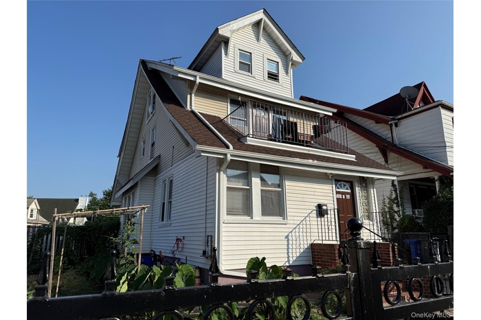 View of front of home featuring a fenced front yard, a balcony, and roof with shingles