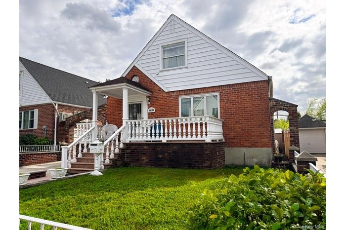 Bungalow-style home with a front lawn, a detached garage, and brick siding