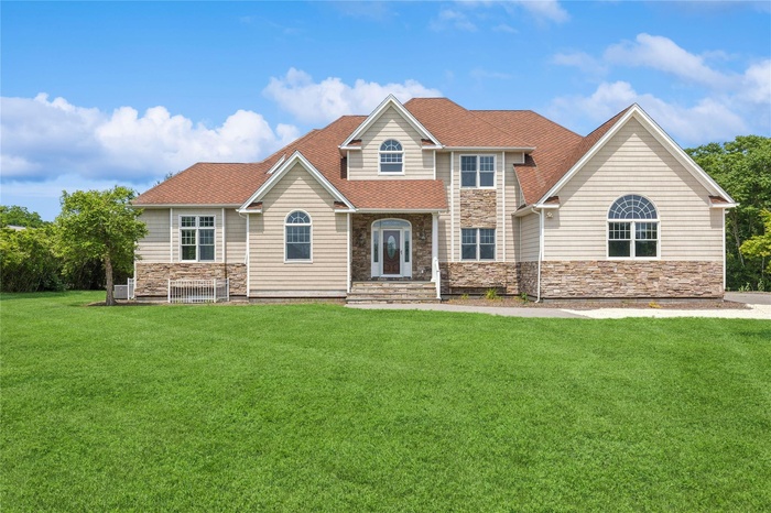 View of front of property featuring stone siding and a front yard