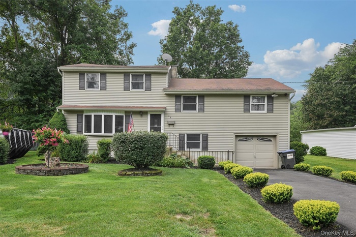 Split level home featuring asphalt driveway, an attached garage, and a front yard
