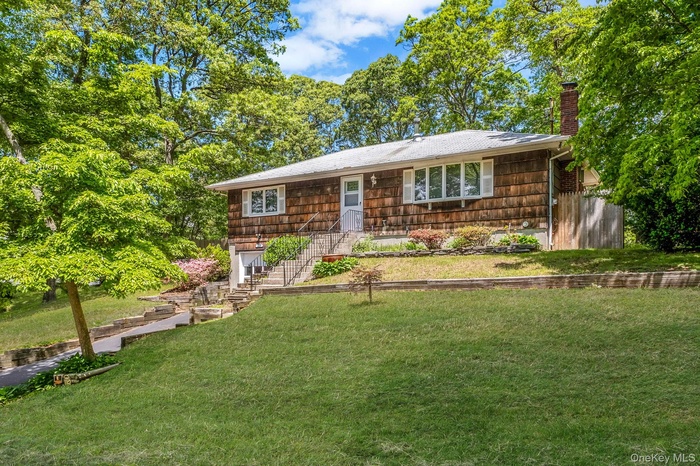 View of front of home with a front lawn, a chimney, and a garage