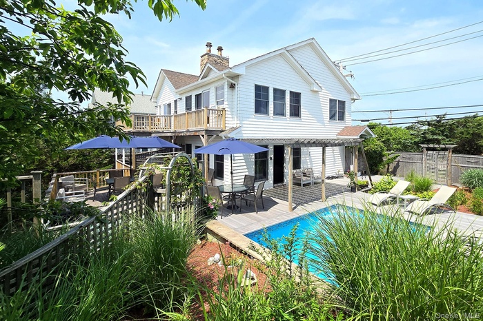 Front of house from Ocean Walk, with a deck, outdoor dining space, a pergola, and a chimney