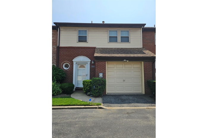 View of front of house with an attached garage, brick siding, and asphalt driveway