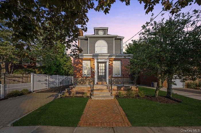 View of property with a gate, brick siding, and a chimney