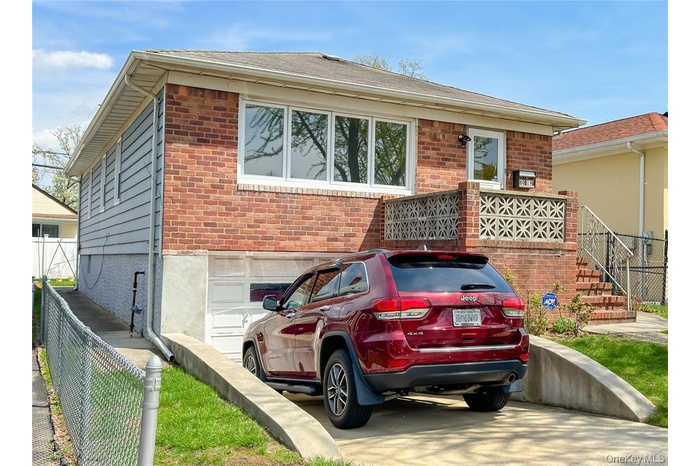 View of front of property with brick siding, an attached garage, and stairway