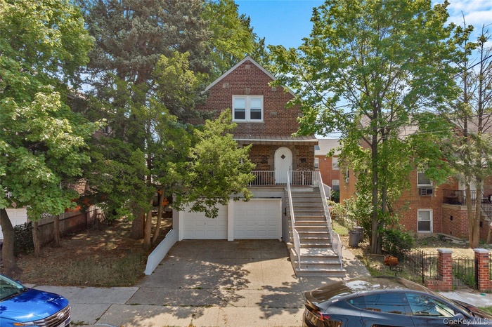 View of front of property featuring brick siding, an attached garage, stairs, and driveway