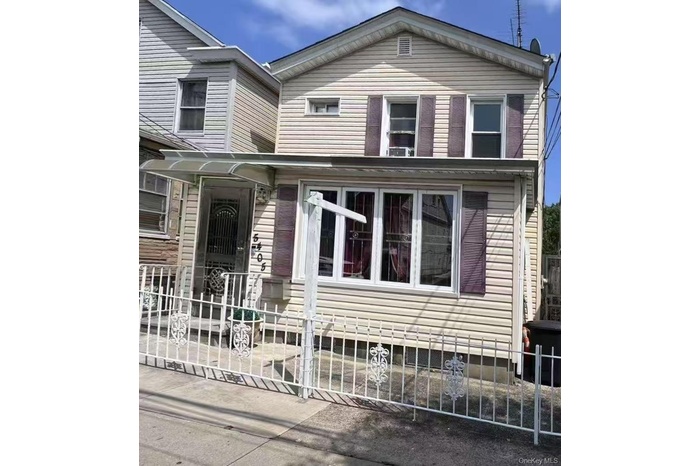 View of side of home featuring a fenced front yard, covered porch, and a gate
