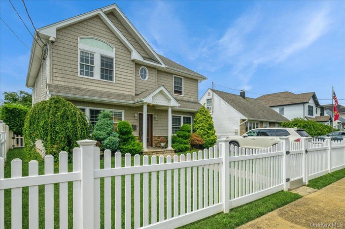 View of front of house featuring a shingled roof and a fenced front yard