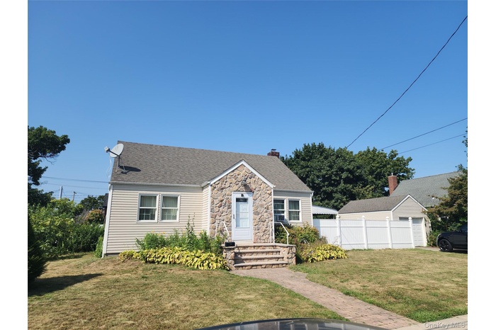 View of front of property with roof with shingles, stone siding, and a chimney