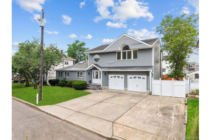 Traditional-style home featuring driveway, an attached garage, and a shingled roof