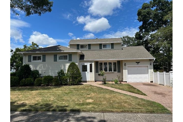 View of front of property featuring a garage with paver driveway