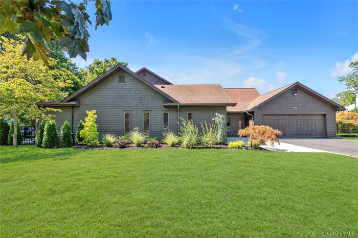View of front facade with a front yard, concrete driveway, a garage, and roof with shingles