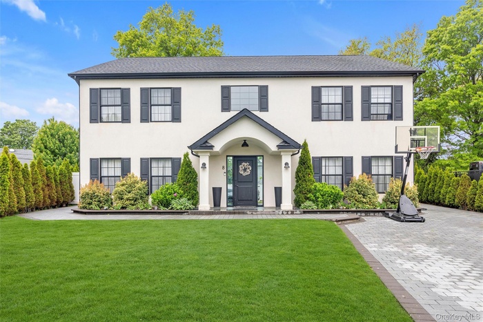 Colonial house with a front lawn and stucco siding