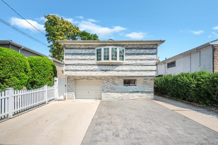 View of front of property with concrete driveway and an attached garage
