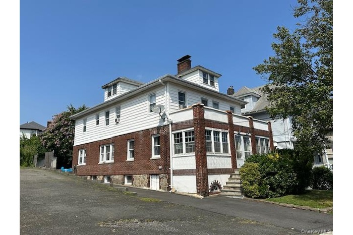 View of home's exterior with a chimney, brick siding, and an attached garage