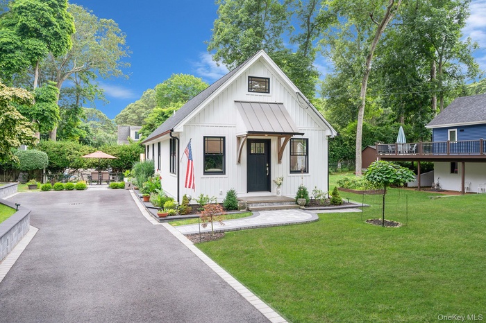 Modern inspired farmhouse with board and batten siding, a front yard, and roof with shingles