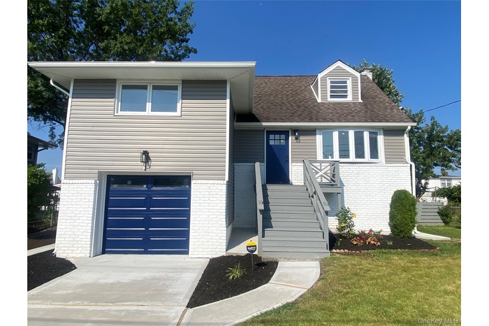 View of front of property featuring an attached garage, brick siding, a chimney, and concrete driveway