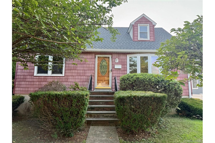 Cape cod-style house featuring roof with shingles