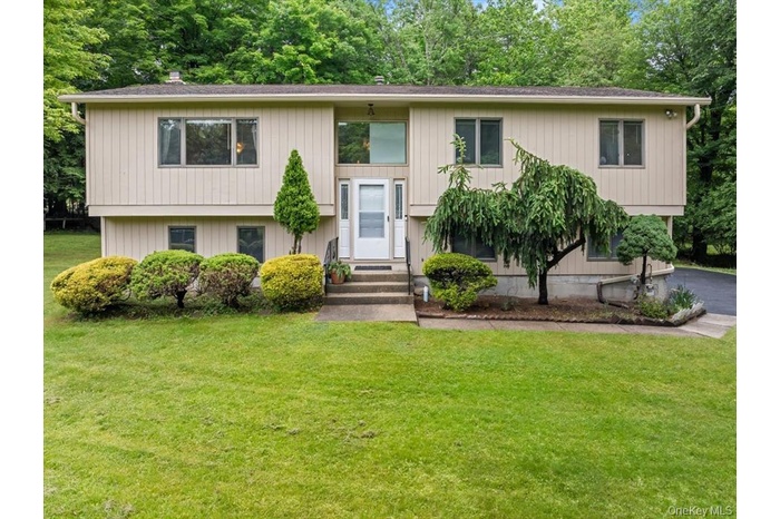 Split foyer home featuring a front yard, asphalt driveway, and entry steps