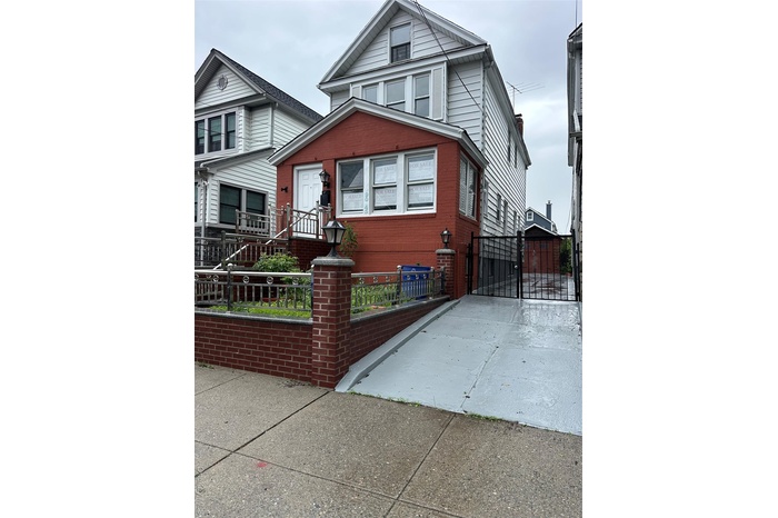 View of front of home featuring a fenced front yard, brick siding, a chimney, and driveway