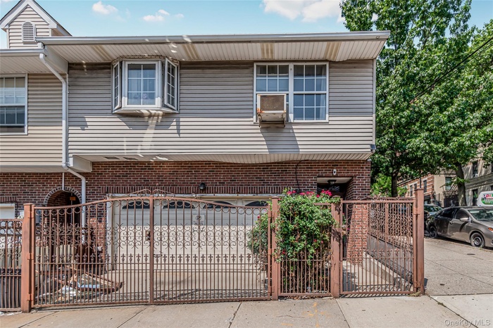 View of front of property featuring a gate, brick siding, driveway, and an attached garage