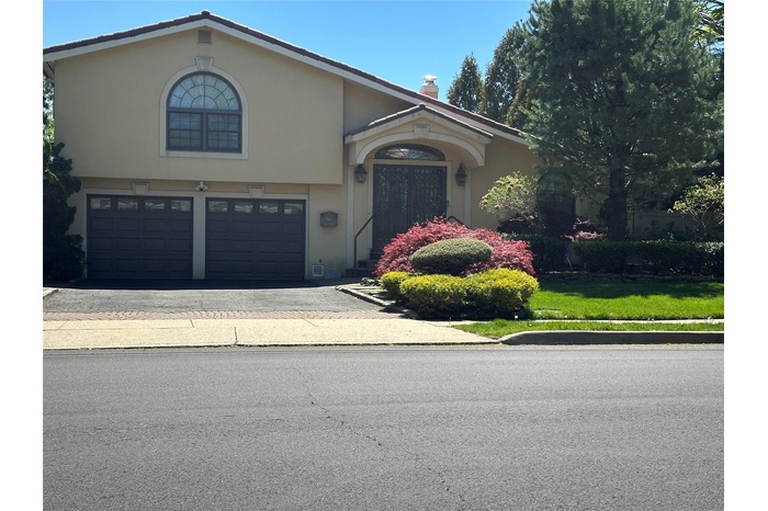 View of front of house with a garage, asphalt driveway, and stucco siding