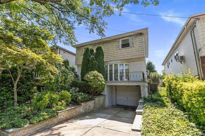 View of front of property with concrete driveway, an attached garage, and a balcony