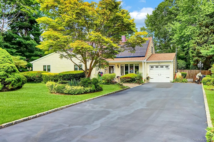 Traditional home featuring roof mounted solar panels, an attached garage, asphalt driveway, and roof with shingles