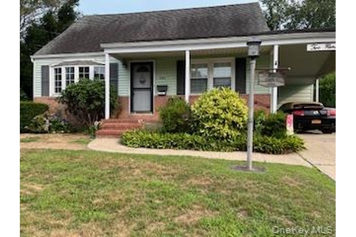 View of front of home featuring a carport, concrete driveway, a front yard, and covered porch
