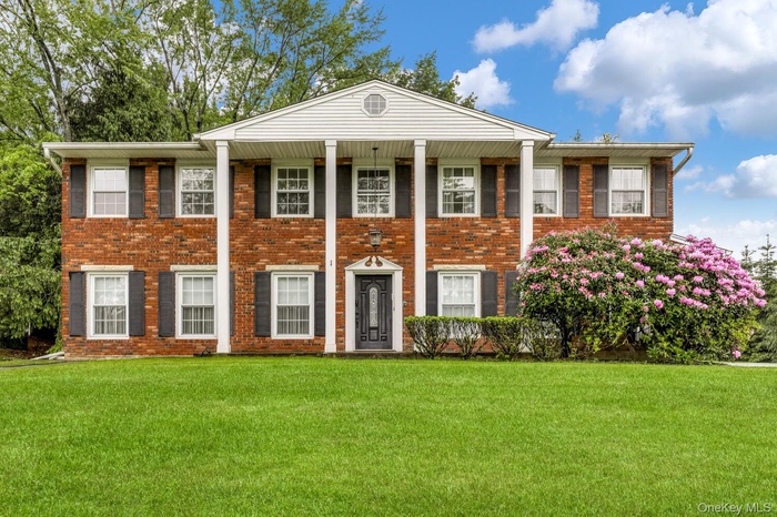Neoclassical / greek revival house with brick siding, a porch, and a front yard