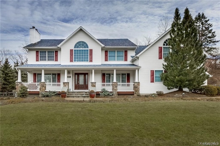 View of front of property featuring a porch, a chimney, a front yard, and roof with shingles
