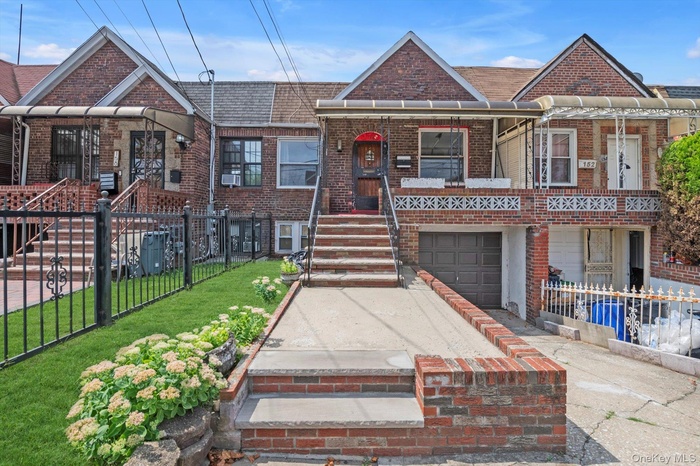 View of front of property featuring a fenced front yard, concrete driveway, brick siding, and a garage