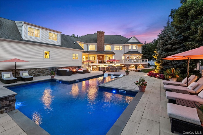 Sunset photo of heated saltwater pool, outdoor kitchen, patio and lighting