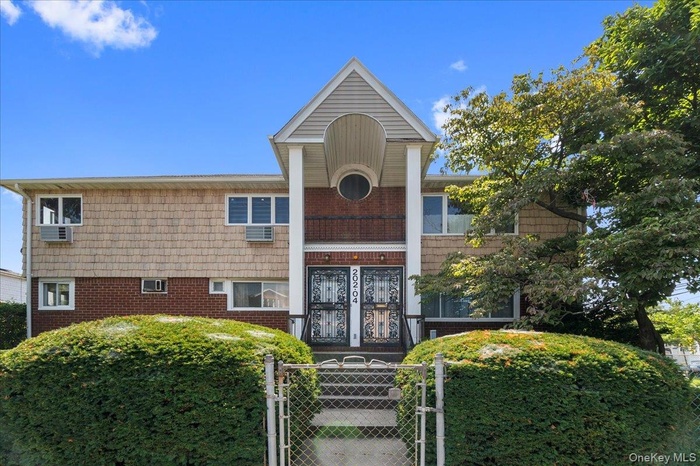 View of front of home featuring a gate, brick siding, and a fenced front yard
