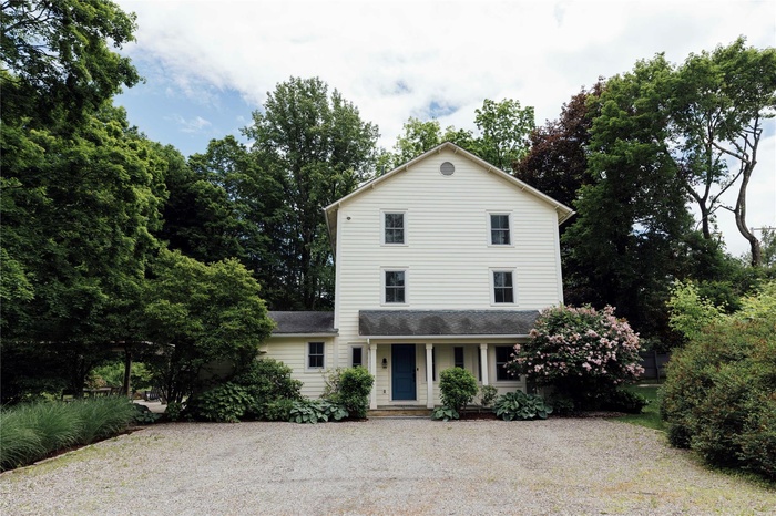 Traditional-style house featuring a porch, driveway, and a shingled roof