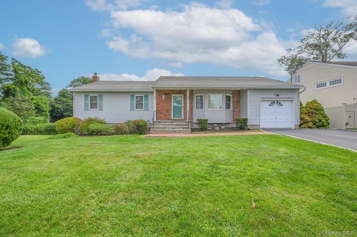 Ranch-style house with driveway, a garage, a front lawn, a chimney, and covered porch