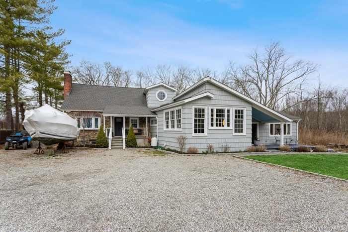 View of front of home featuring gravel driveway, a shingled roof, and a chimney