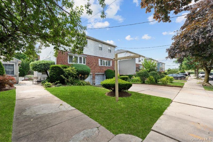 View of front facade featuring brick siding, driveway, an attached garage, and a front yard