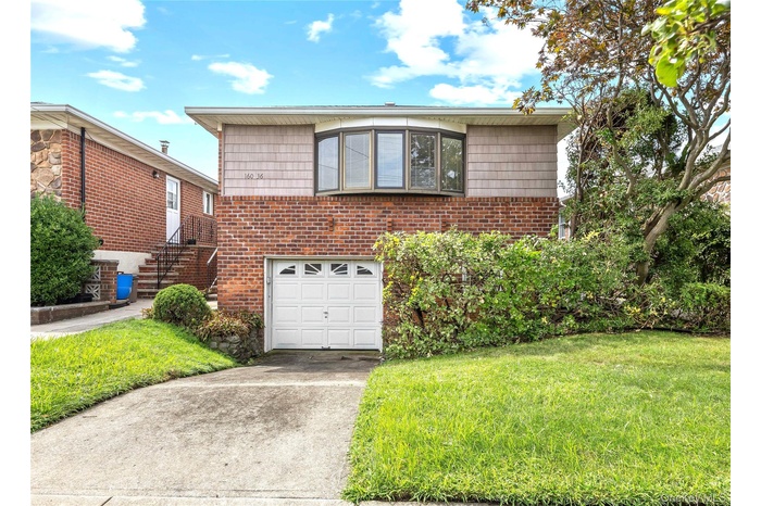 View of front of house with a garage, a front yard, driveway, and brick siding