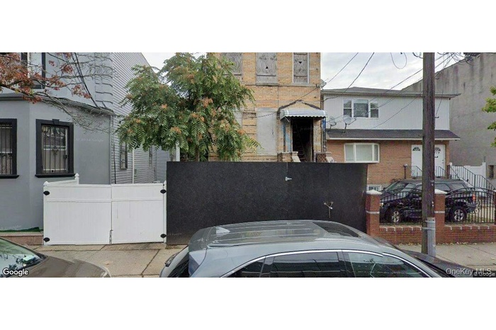 View of side of home featuring a fenced front yard, brick siding, and a gate