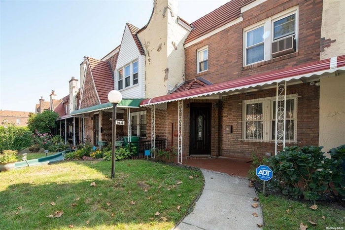 View of property featuring brick siding and a front lawn