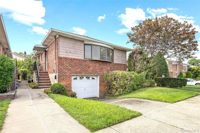 View of front of property with a garage, brick siding, concrete driveway, stairs, and a front lawn