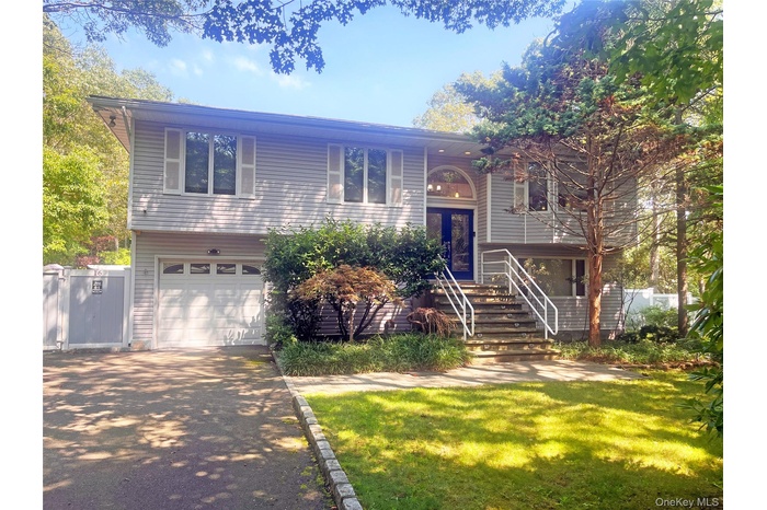 Split foyer home with driveway, an attached garage, and stairway